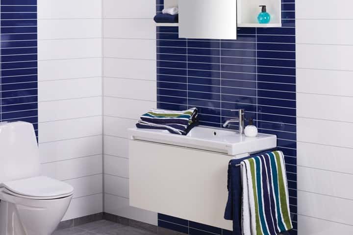 Toilet en wastafel tegen donkerblauwe en witte hoogglans panelen, met kleurrijke handdoeken.