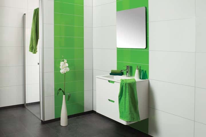 Badkamer met groene hoogglans panelen naast witte panelen, een wit wastafelmeubel en groene handdoeken.