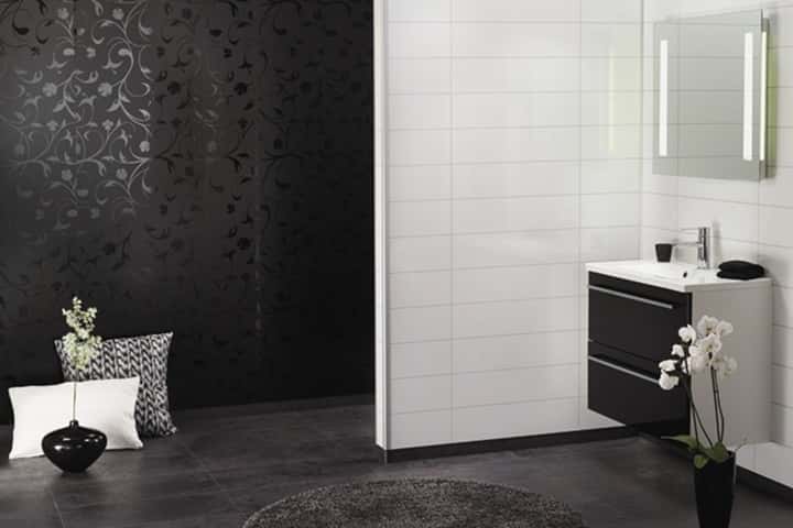 Donkere wand met zwart bloemdessin naast een witte tegelwand, met een zwarte wastafelkast en een witte orchidee.
