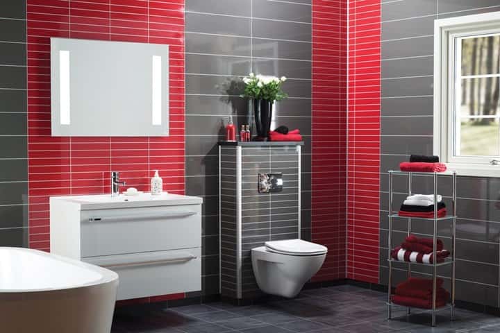 Badkamer met felrode wandpanelen achter het toilet, grijze wandpanelen, een wit ligbad en een witte wastafelkast.
