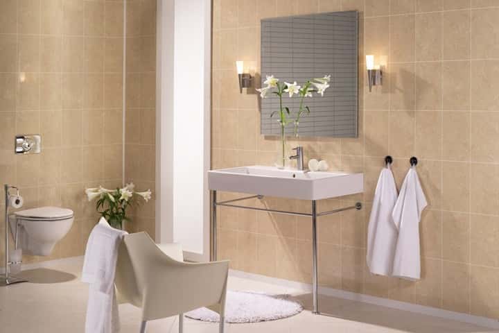 Badkamer met warm beige wandpanelen, een witte wastafel op een chromen frame, wandlampen en witte handdoeken.