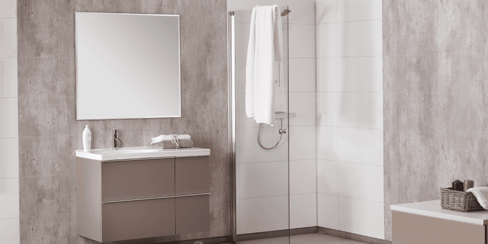 Badkamer met betonlook-wandpanelen, een wit wastafelmeubel met spiegel en een inloopdouche.